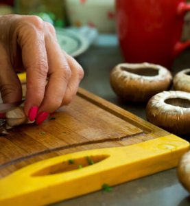 יד חותכת פטריות על קרש חיתוך - אוכל גורמה צרפתי