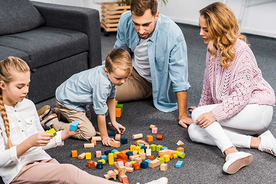 משפחה משחקת במשק קופסא על השטיח